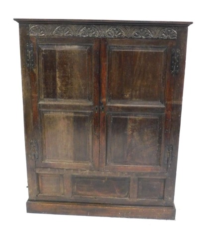 An 18thC adapted oak cupboard, with demi lune carved frieze, fielded panelled doors and panelled base, 156cm high, 123cm wide, 52cm deep.