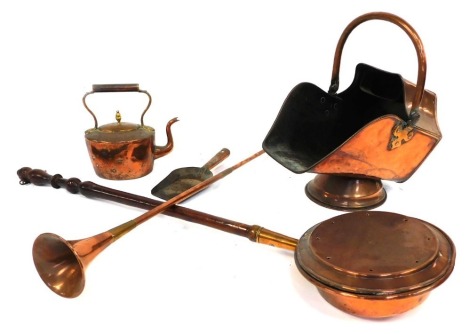 A group of copper and brass wares, comprising a copper warming pan with turned wooden handle, 110cm long, a 19thC copper coal scuttle, with shovel, 18cm high, kettle lacking lid, and a coaching horn. (4)