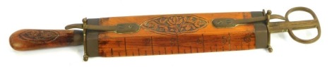 An Indian cased tailor's knife, with twin blade and scissor end, with tape measure centre, carved wooden sheath, 32cm long.