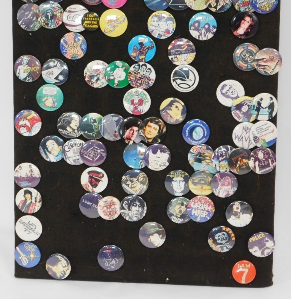 A cork board with band pin badges for Aerosmith, The Eyes, Thin Lizzy, Hawk  Wind and others, 123cm x 60cm.