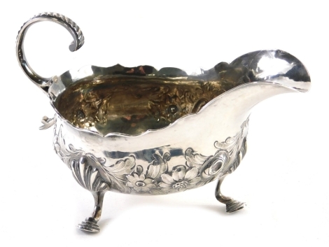 A George III silver sauce boat, by Imperial Mint, with flying scroll handle, repousse decorated floral body, on stepped hoof feet, London 1763. 10cm high, 5oz.