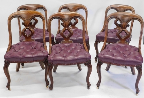 A set of six Victorian mahogany spoon back dining chairs, each with a pierced Gothic style quatrefoil to the back, purple buttoned leather padded seats, on cabriole legs.