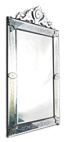 A Venetian wall mirror, the rectangular bevel plate flanked by leaf and floral engraved borders embellished by oval and shield shaped mounts, the shield shaped crest flanked by foliate scrolls, 171cm high, 91cm wide.