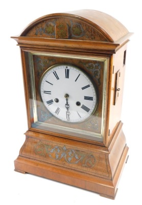 A 19thC walnut cased cuckoo clock, the 18cm diameter Roman numeric dial, in an arched case with a silvered floral inlay, scroll spandrels and bracket feet, with a eight day movement striking on the hour with pendulum and key, 45cm high