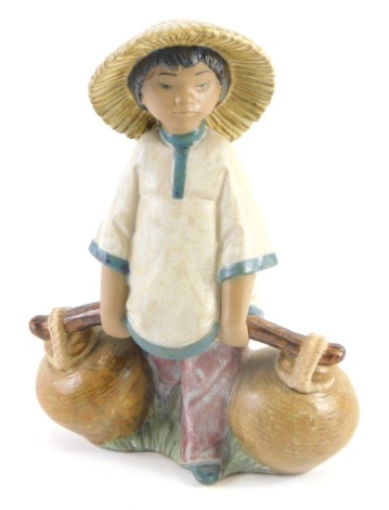 A Lladro ceramic figure of an Oriental child carrying water, 19cm high.