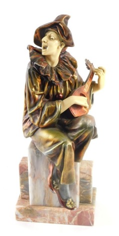 An Art Deco style gilt and copper patinated spelter figure of Pierrot, seated on a marble base, 34cm high.