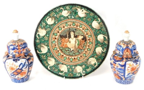 A 19thC pottery plate, possibly Indian, centred with a figure and cattle, with a goose and floral surround, polychrome decorated predominantly in green and brown, marked verso, and two 19thC Imari vases. (3, AF)