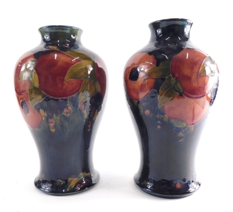 A large pair of early 20thC Moorcroft pottery Pomegranate pattern vases, each of inverted shouldered form, impressed and green signature marks beneath, 35cm high. (2, 1 AF)