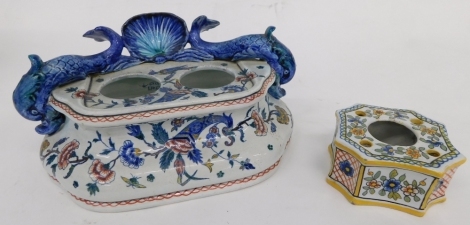 A 20thC Cien tin glazed earthenware part ink stand, with dolphin and shell top, profusely decorated with flowers, cornucopia and birds, 21cm wide, and a further Maiolica ink stand, of inverted square form, profusely decorated with flowers. (2)