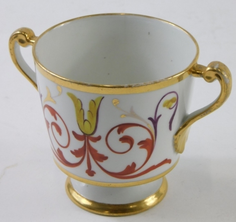 A 20thC porcelain loving cup, decorated with scrolls and flower heads, on a white ground, on stepped circular base with gilt highlights, unmarked, 9cm high.