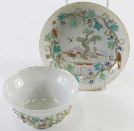 A 19thC porcelain tea bowl and saucer, hand painted with animals and trees, with a raised border of further flower heads, predominately in blue, pink, and green, with gilt highlights, the bowl, 10cm diameter, unmarked. (2)