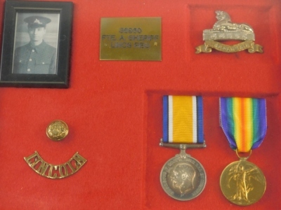 A WWI medal group, comprising Campaign and Victory medals, Lincoln shoulder badge, brass button, and Lincoln Sphinx badge, with photograph, in case marked 36960 PTE A SHERIFF Lincs Reg, the case 25cm x 31cm.