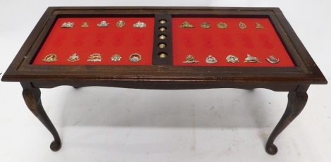 A 20thC coffee table set with various cap badges and brass buttons, Norfolk Regiment, 6cm wide, Manchester, Tank Corps badge etc. (a quantity)