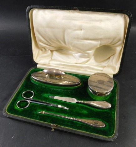 A George V silver mounted manicure set, with scissors, jar and cover, nail buffer etc. Birmingham 1918 and 1919 and two sets of silver handled dessert knives all in fitted case.