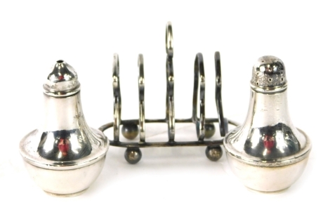 A George V small silver four division toast rack on ball feet, Birmingham 1912 (AF) and a pair of pepper pots each with Bakelite liners, 3.34oz all in.