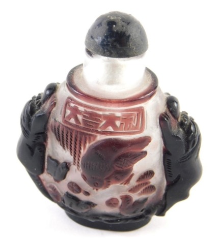 A Chinese Peking glass snuff bottle, with animal handles in purple on frosted glass ground with compressed stopper, 7cm high.