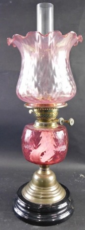 A 20thC oil lamp, with clear glass funnel, amethyst coloured glass ribbed shade, cranberry style reservoir, on circular socle, 59cm high.