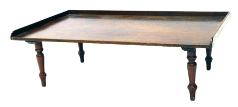 A 19thC mahogany galleried edge invalid bed tray, on turned legs, 23cm high, 72cm wide, 44cm deep.