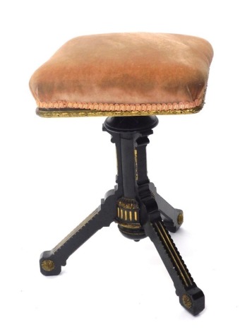 An Edwardian Aesthetic style ebonised and gilt highlighted stool, with square overstuffed top, on turned stem and shaped legs with floral patera, 58cm high, 37cm wide, 33cm deep.