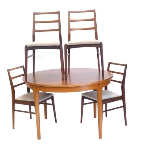 A 1970s teak extending dining table and four chairs, each with drop in seats in cream material, the table when closed 76cm high, 113cm wide, 122cm deep. The upholstery in this lot does not comply with the 1988 (Fire & Fire Furnishing) Regulations, unless 