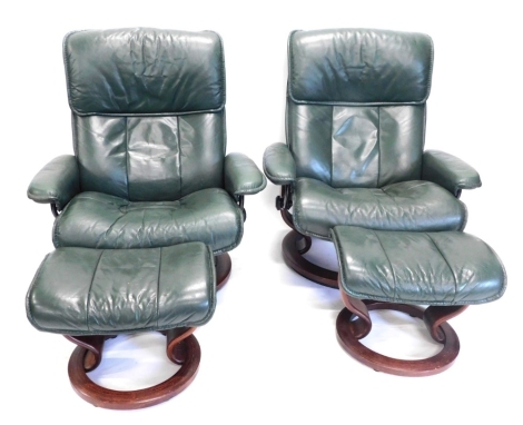 A pair of 20thC green leather swivel lounge chairs, 103cm high, with footstools. (4)