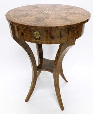 A 20thC Italian inlaid and ebonised occasional table, the segmented veneer type top centred with a star stencilling, above frieze drawers with lion mask handles, on inverted sabre legs joined by an inverted stretcher, 75cm high, 55cm diameter.