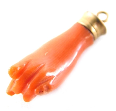 A coral fist pendant, formed as a hand forming fist, lacking forefinger, in a yellow metal pendant mount, 2.5cm high, 1.4g all in. (AF)