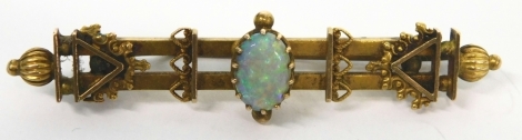 An early 20thC bar brooch, claw set with central opal, of fancy design with plain pin back, marked 15, 5cm long, 3.8g all in.