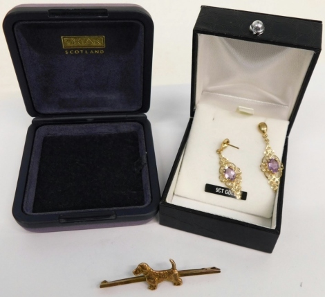 A pair of 9ct gold earrings, with pierced diamond shaped backs, claw set with purple stones, 3cm high, 1.4g all in, and a gold plated brooch with dog charm front. (2)