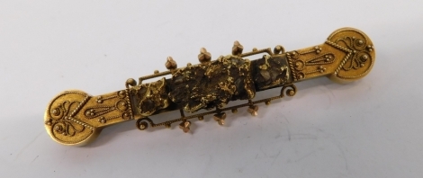 An elaborate early 20thC brooch, with a blind fret scroll decoration centred by shaped sections, with plain pin back, unmarked, 7cm long.