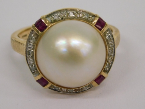 A 9ct gold pearl, ruby, and diamond dress ring, the central blister pearl, in a rub over setting with four baguette cut ruby markers, and halo of outer round brilliant cut diamonds, yellow metal band stamped 375, 3.9g all in.