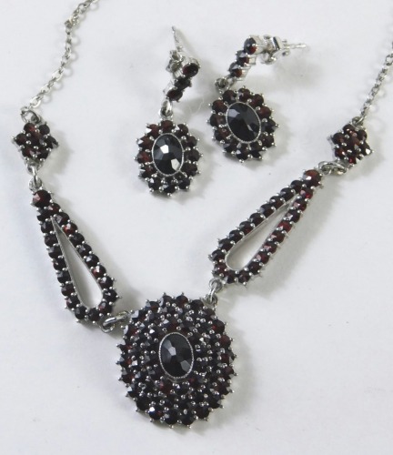 An imitation garnet necklace and earring set, in late Edwardian style with layered centre and teardrop pendants, in plated mounts.