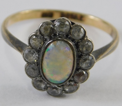 A 9ct gold and silver opal dress ring, the oval stone surrounded by small white stones, size N, 2g all in.