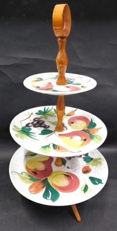 A three tier Italian pottery and wooden cake stand, painted with flowers, on wooden stand, with circular pottery sections, 44cm high.