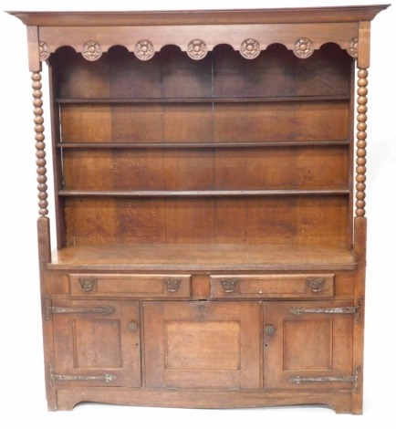 A 19thC Arts and Crafts dresser, with plate rack top, having rose carved frieze, bobbin turned supports, boarded plate rack, over two drawer base and three cupboards, marked Burke Beck verso, 207cm high, 108cm wide, 50cm deep.