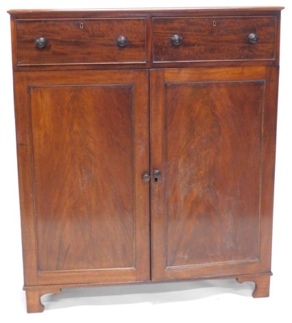 A Regency mahogany cabinet, with two drawers over two panelled doors with press interior drawers, on bracket feet, 115cm wide.