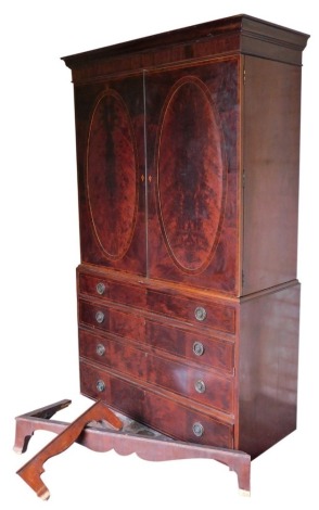 A Regency flame mahogany linen press, with moulded cornice, two oval panelled doors over four graduated drawers, with brass ring handles, on bracket feet, 220cm high, 125cm wide.