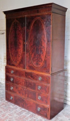 A Regency flame mahogany linen press, with moulded cornice, two oval panelled doors over four graduated drawers, with brass ring handles, on bracket feet, 220cm high, 125cm wide. - 2