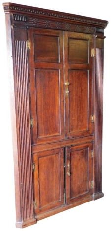 A George II oak freestanding corner cupboard, with key moulded cornice, blind fret work frieze, scoop carved sides enclosing two over two panelled doors, 210cm high, 115cm wide.