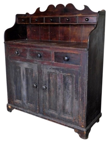 A Victorian stained pine kitchen dresser, with shaped top, having five spice drawers with knob handles, three drawers over two panelled doors, and bracket feet, 150cm high, 130cm wide, 55cm deep.
