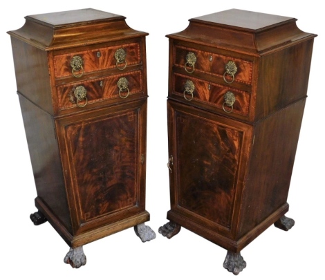 A pair of Edwardian Sheraton Revival pedestals, stamped Phillips of Bristol, with cross banded decoration, having cavetto tops, two drawers with lion mask ring handles, and cupboard bases, 120cm high, 52cm square. (loss to one of the feet)