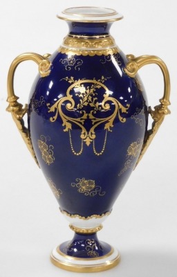 A Royal Crown Derby porcelain twin handled vase, circa 1907, decorated centrally with a floral reserve within a gilt shield shaped floral embellished border, against a cobalt blue ground, with gilt handles and gilt banding, stamped to underside and number - 2