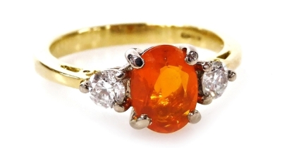 An 18ct gold and three stone fire opal and diamond dress ring, with oval cut fire opal, 7.6mm x 5.8mm x 3.6mm, flanked by two round brilliant cut diamonds, each approximately 0.15ct, ring M½, 4.2g all in.