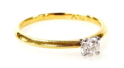 An 18ct gold and diamond solitaire ring, with a round brilliant cut diamond totalling 0.24ct, in a four claw white gold setting on a yellow metal band, ring size M½, 2g all in.