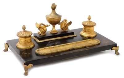 A 19thC French Empire bronze and ormolu double encrier, the two ink receivers with hinged lids and acanthus decoration, the central pounce pot urn flanked by two swans and with gadrooned pen tray, the rectangular stand raised on four paw feet, 16.5cm high