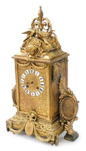 A late 19thC French gilt metal mantel clock, with black and white enamelled Roman numerals, the highly ornate case surmounted with love birds above a masked head, swag ornamentation and oval cameos, housing an eight day striking movement, 40cm high.