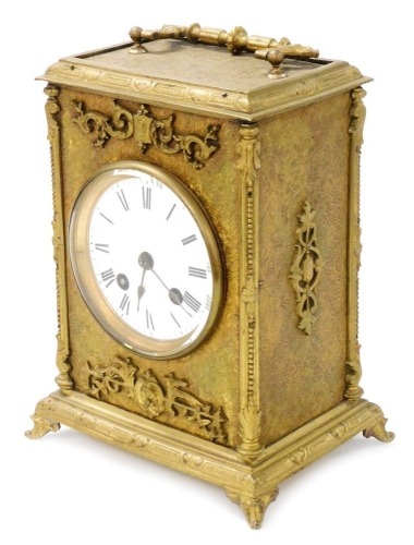 A late 19thC gilt cased mantel clock, with eight day striking movement, having white enamel dial and Roman numerals, the case with rococo scroll decoration and feet, 23cm high. (handle down)