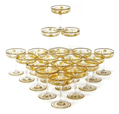 A suite of eighteen late 19thC Continental champagne coupes, possibly St Louis, the shallow circular bowls with gilt borders and engraved with flower heads and grapes with foliate scrolls, heightened in gilt, on slender stems and circular feet, 10.5cm hig