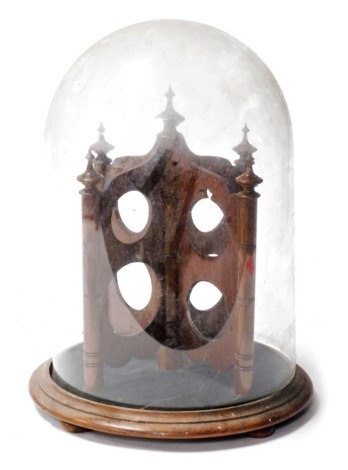 A rosewood stand, with fret work piercings possibly for pocket or fob watches, contained within a glass dome, on a turned base, 34cm high.