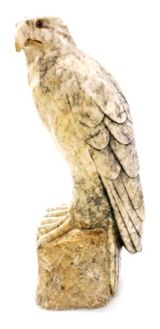 A 19thC Continental carved alabaster figure of an eagle, with glass eyes, perched on a stylised rock base, 46cm high.